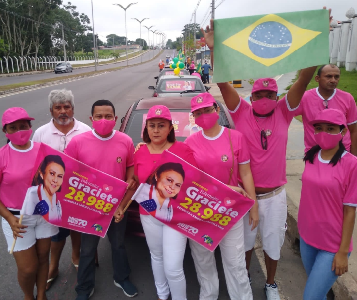 Ativistas brasileiros em camisas rosa, máscaras e chapéu mostrando pancarts para Graciete